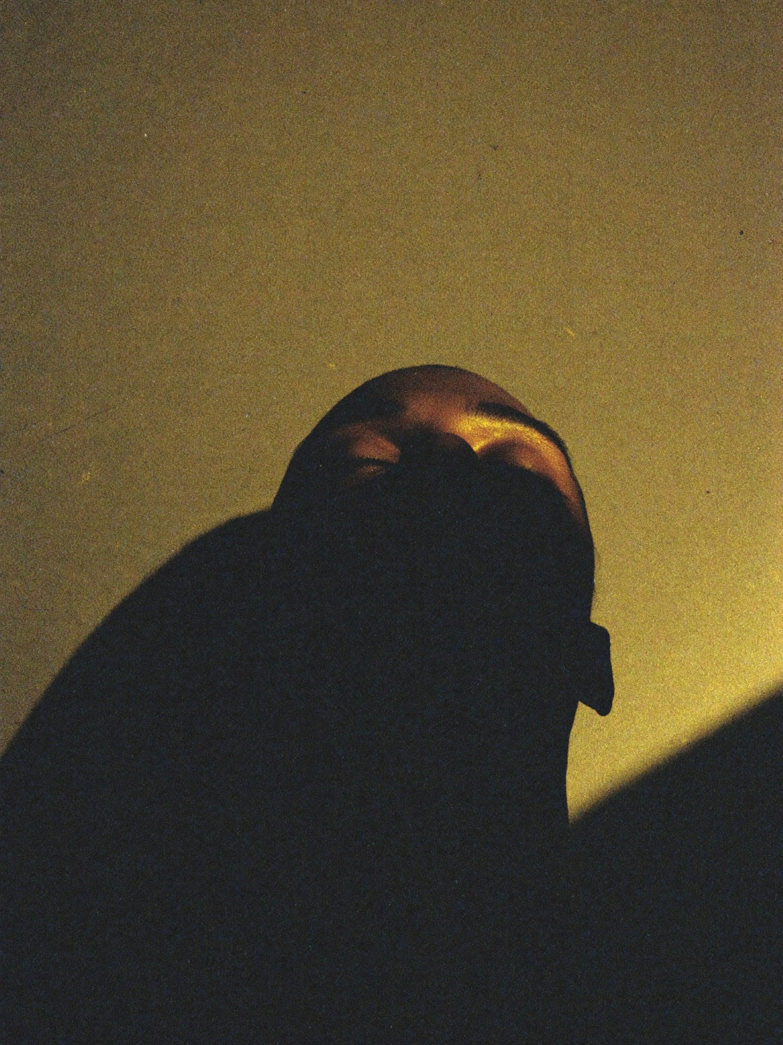 A face tilted back into warm gold light, lost in a remembered moment.