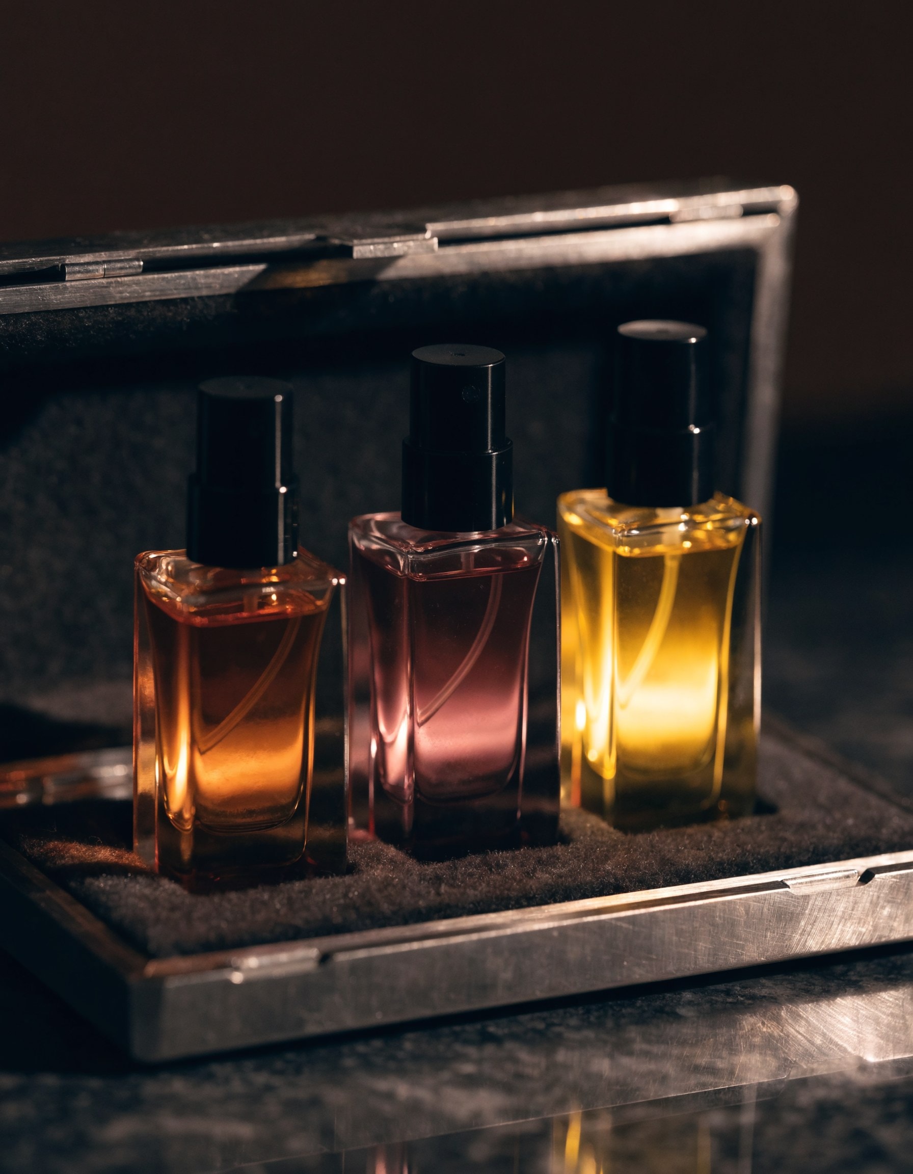 The Atelier Set — three flacons of SÉVE, CENDRE and HÉLIA in an open machined travel case.