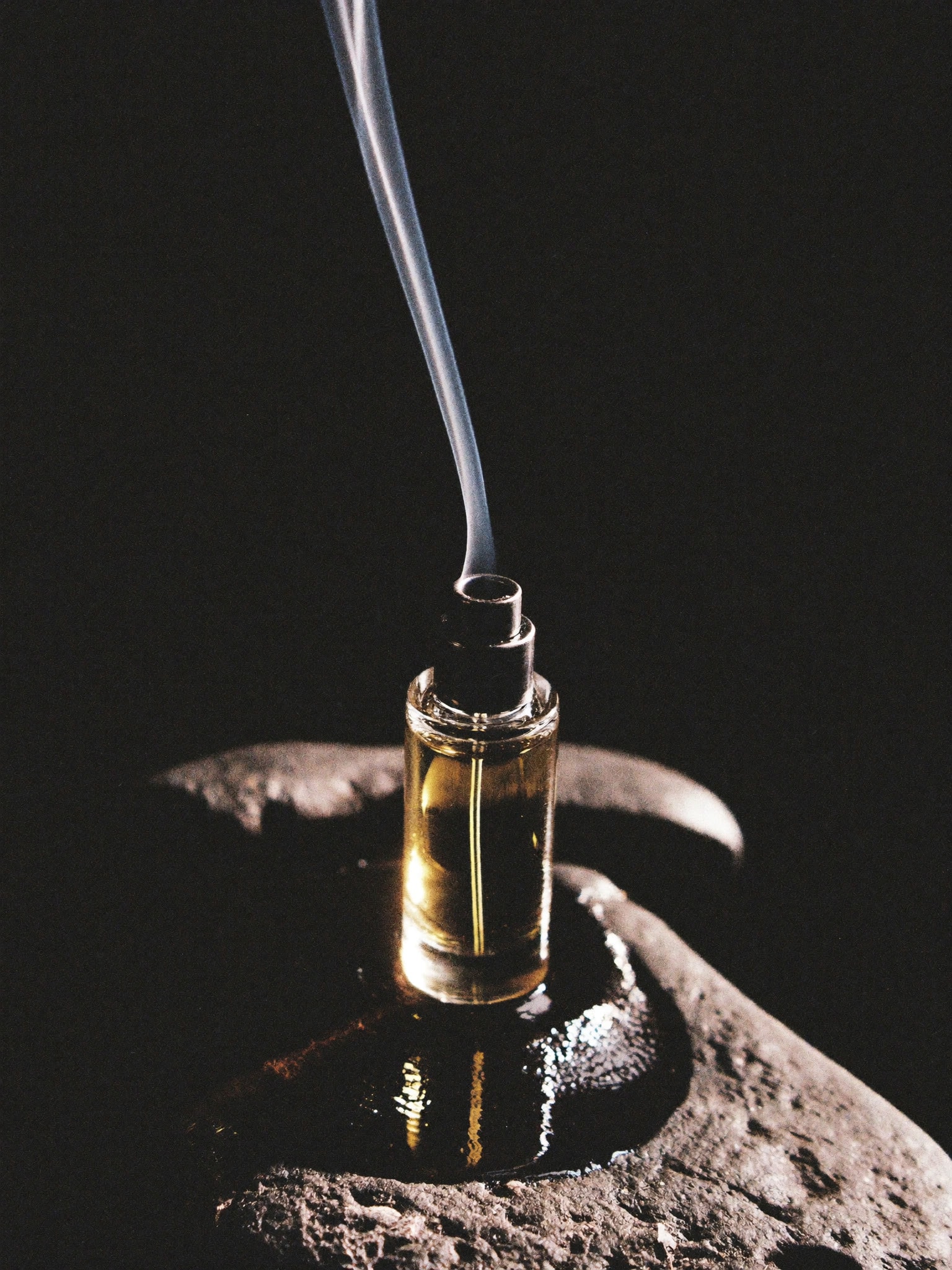 SÉVE Travel — a small refillable atomiser on wet black stone, smoke rising.